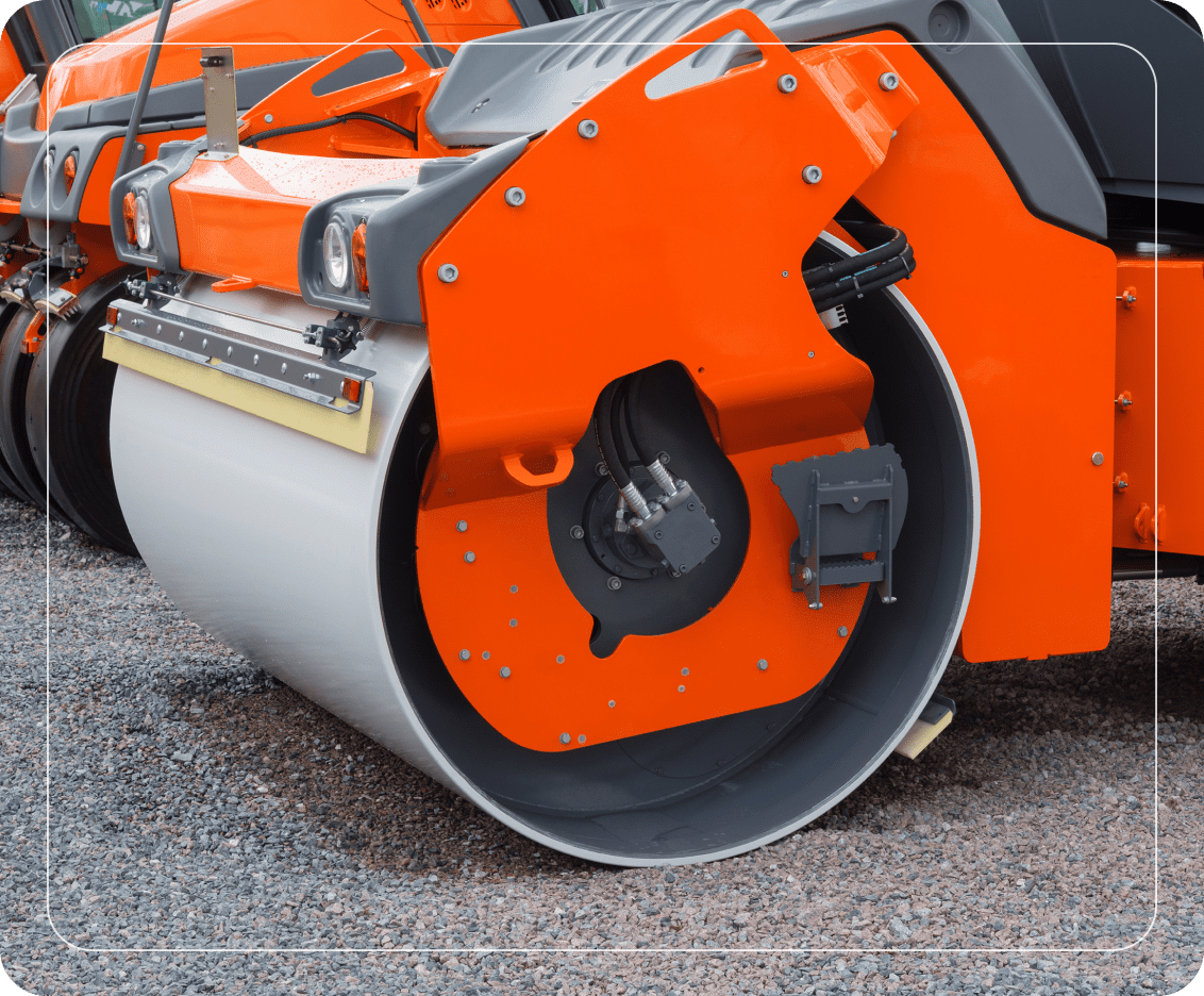 Orange road roller on gravel surface.